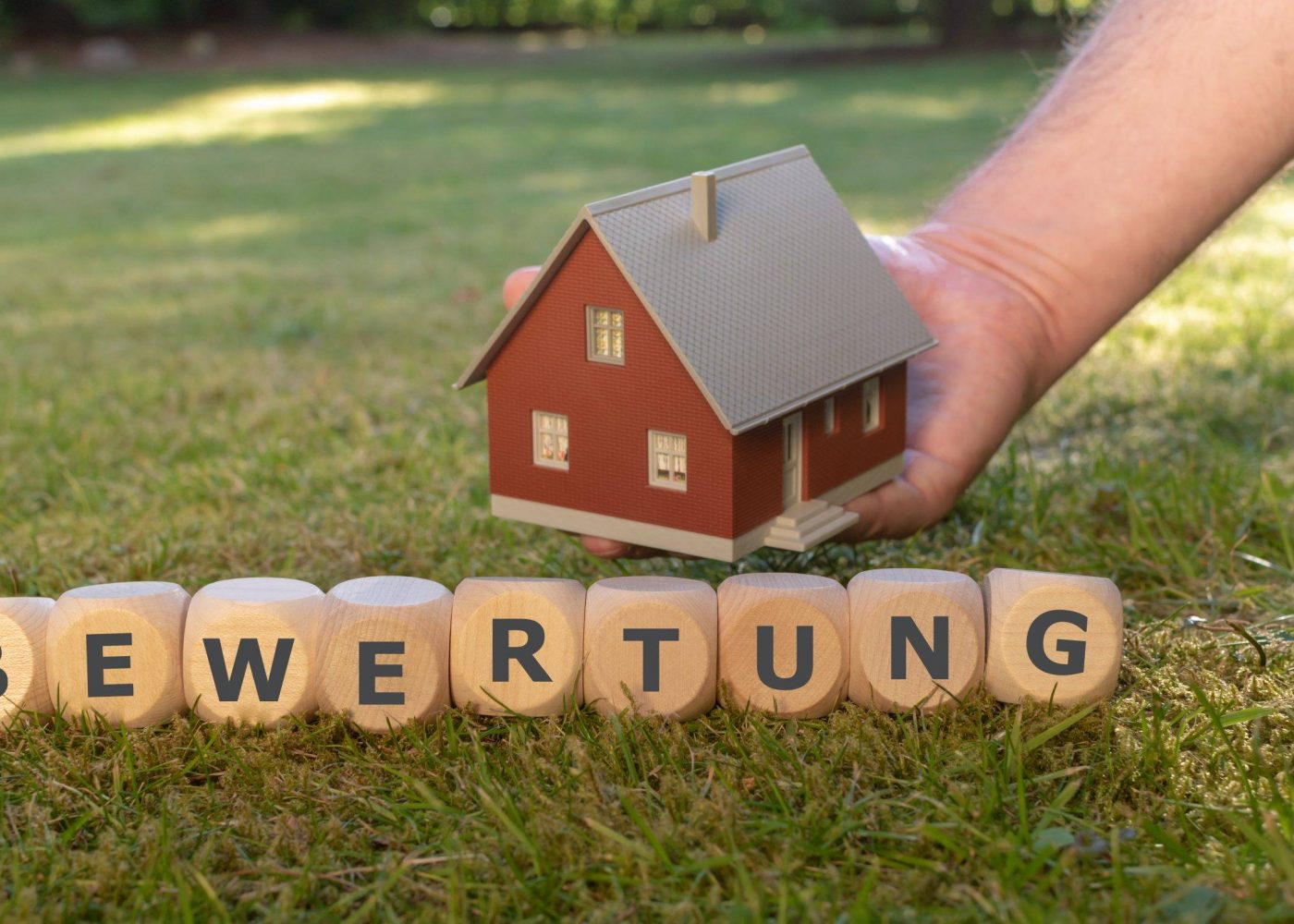 Cubes form the German word "Bewertung" ( "appraisal" in English) in front of a model house.